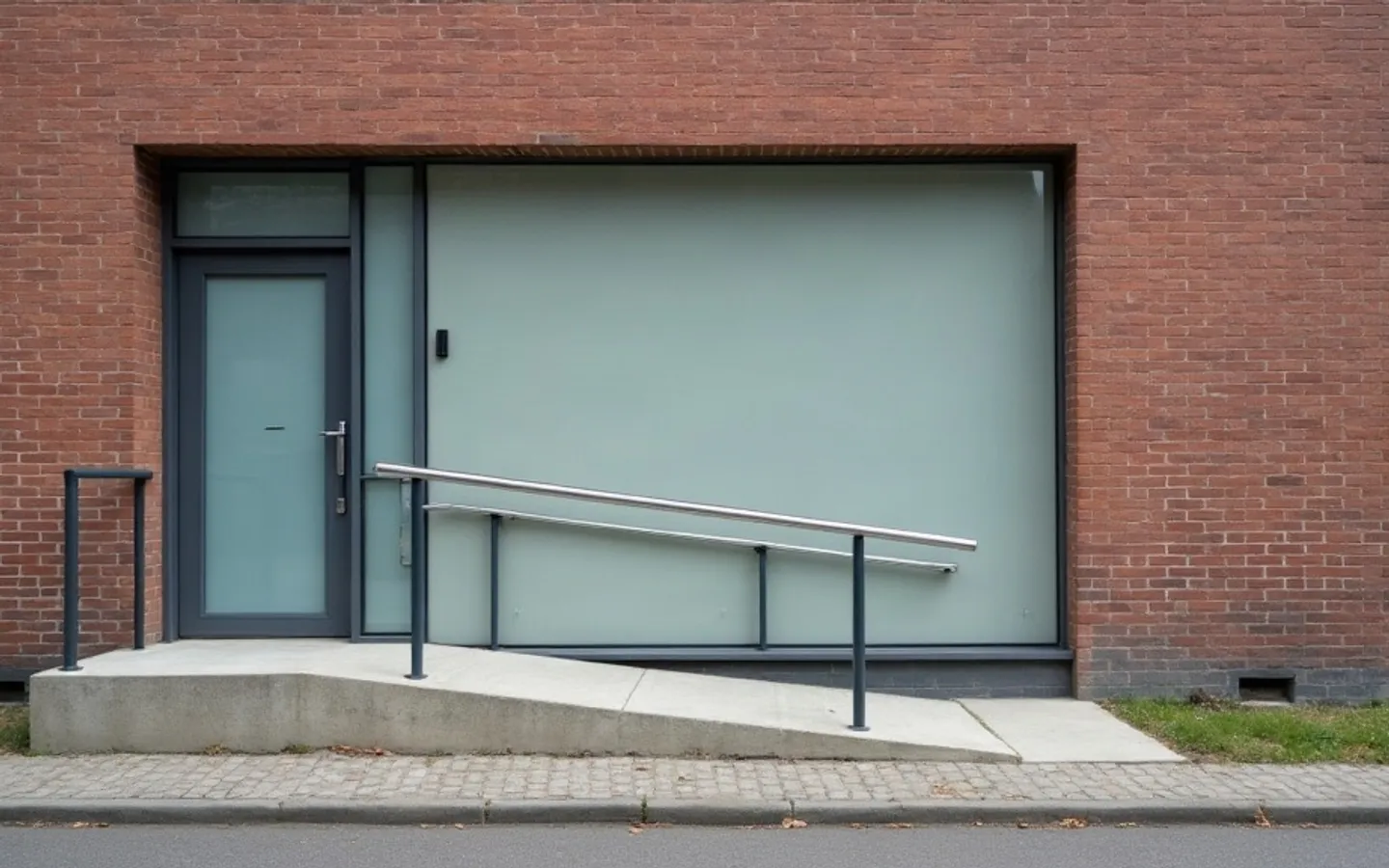 Praktijkingang in een bakstenen gevel, met matglas en een metalen hellingbaan naar de deur