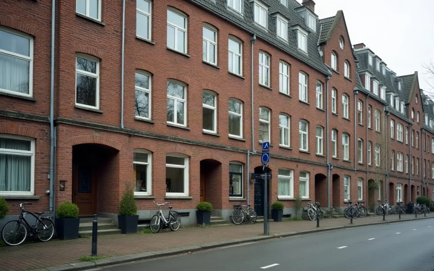 Straat met aaneengesloten bakstenen panden, waarvan de begane grond ramen en deuren op de stoep heeft